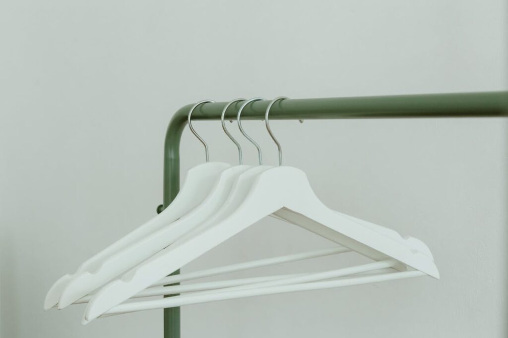 Closeup of white hangers on a modern metal clothing rack, ideal for fashion stock images.